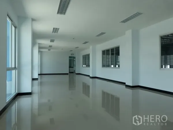 Factory for rent in Bang Sao Thong, Samut Prakan - Second-floor office corridor with fluorescent lighting, windows to the warehouse and shiny tile flooring.