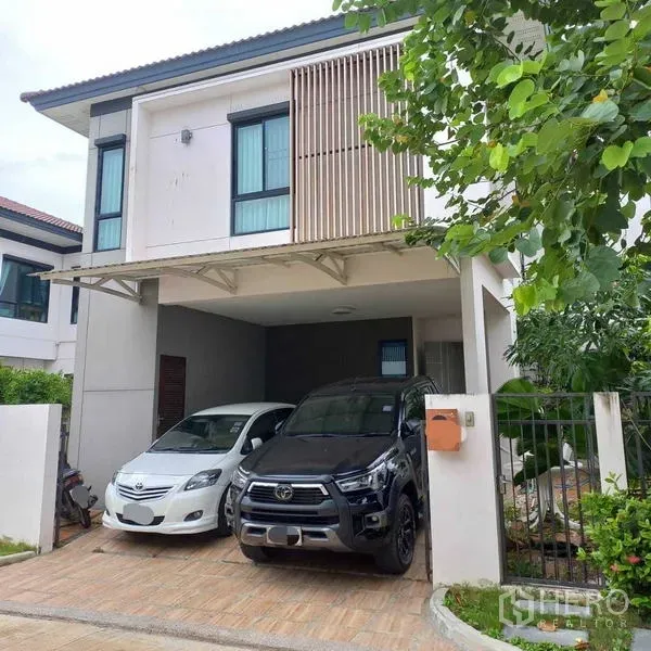 บ้าน ให้เช่าในBang Khun Thian, Bangkok - มุมหน้าบ้านมีรถจอดใต้หลังคาได้ 2 คัน กระจกบานใหญ่ชั้นบนและสวนข้างบ้านขนาดกะทัดรัด