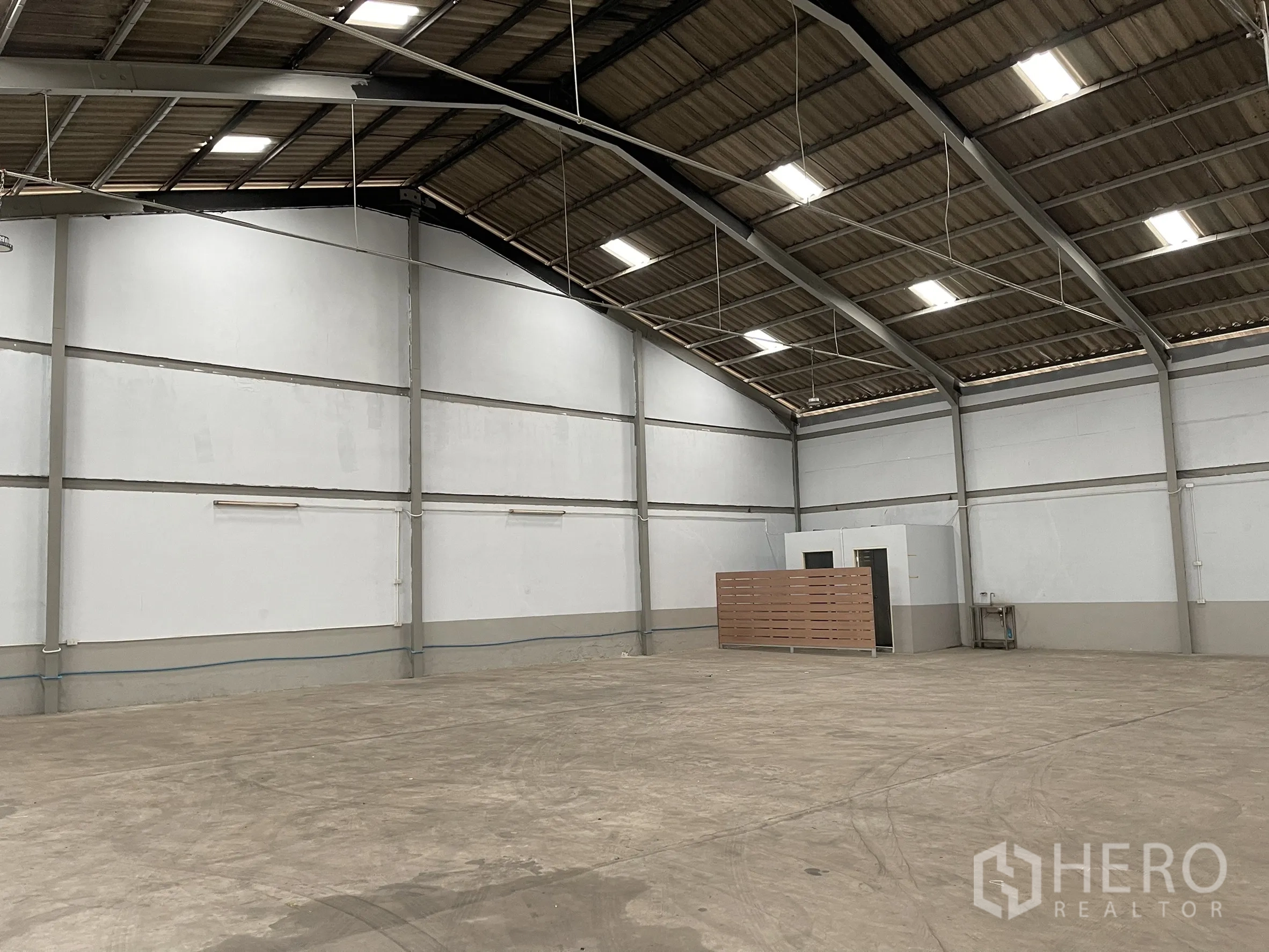 Factory for rent in Mueang Samut Prakan, Samut Prakan - Spacious factory interior with high steel roof, concrete floor, and small partitioned rooms.