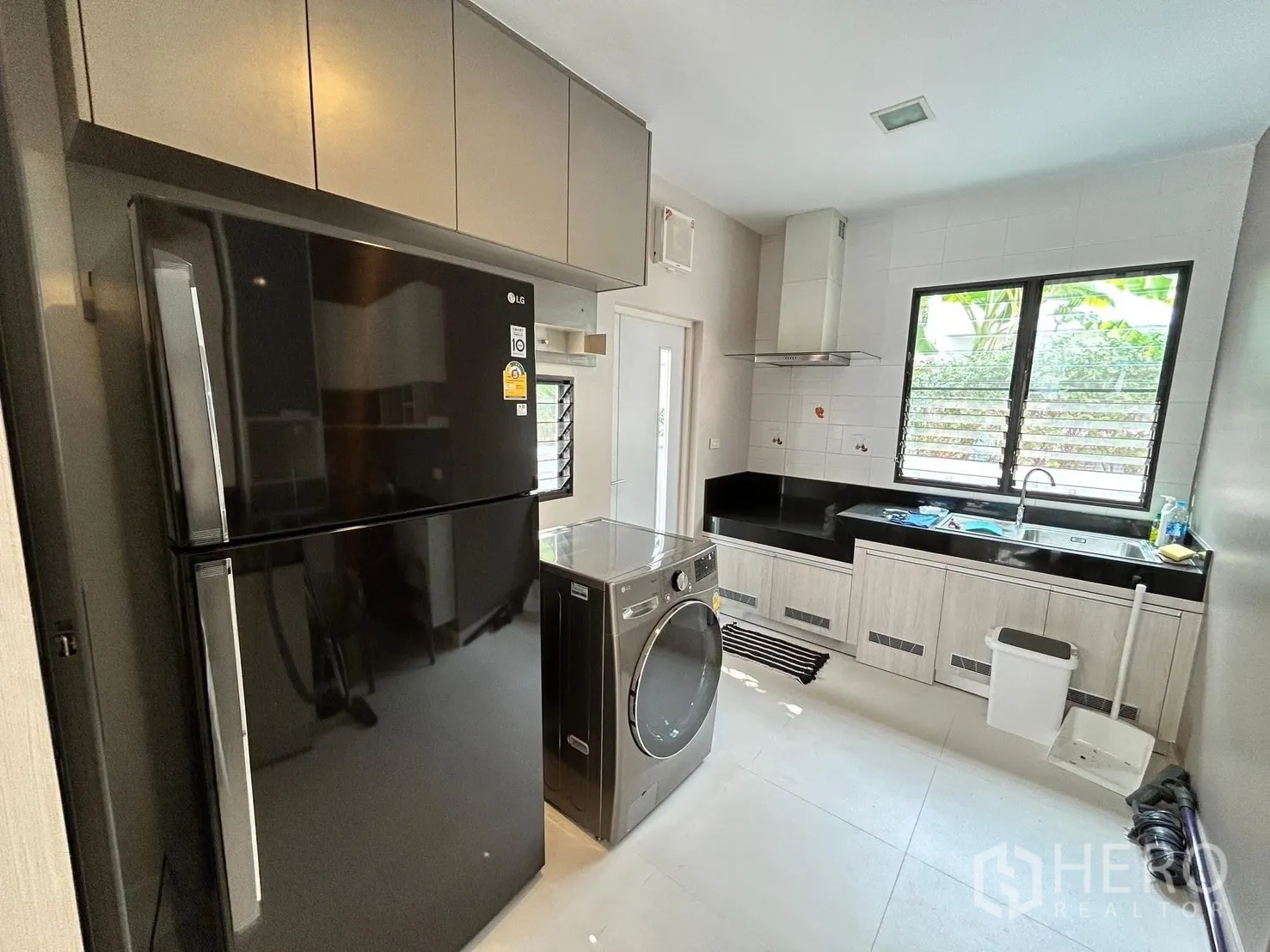 独栋房屋 for rent or sale in Prawet, Bangkok - 现代厨房，黑色冰箱、洗衣机，L形料理台、抽油烟机与水槽。