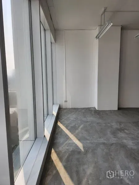 办公空间 出租在Sathon, Bangkok - 明亮角落，整面落地窗与混凝土地面，采光充足。