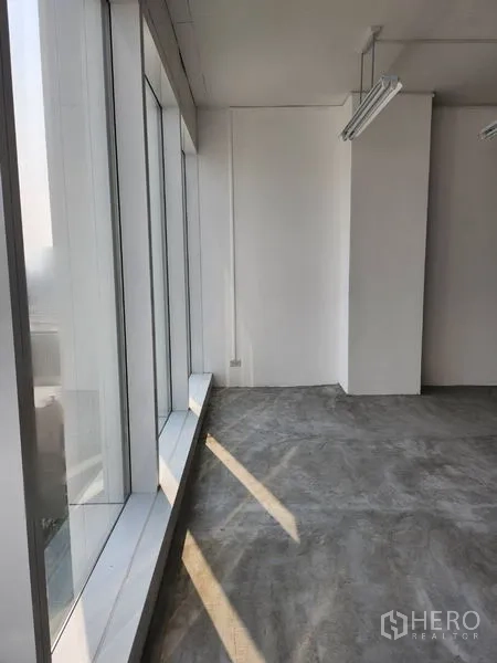 办公空间 出租在Sathon, Bangkok - 明亮角落，整面落地窗与混凝土地面，采光充足。