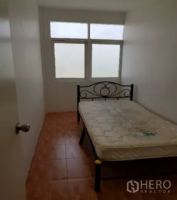 Shophouse for rent in Watthana, Bangkok - Compact bedroom with metal bed frame and window.