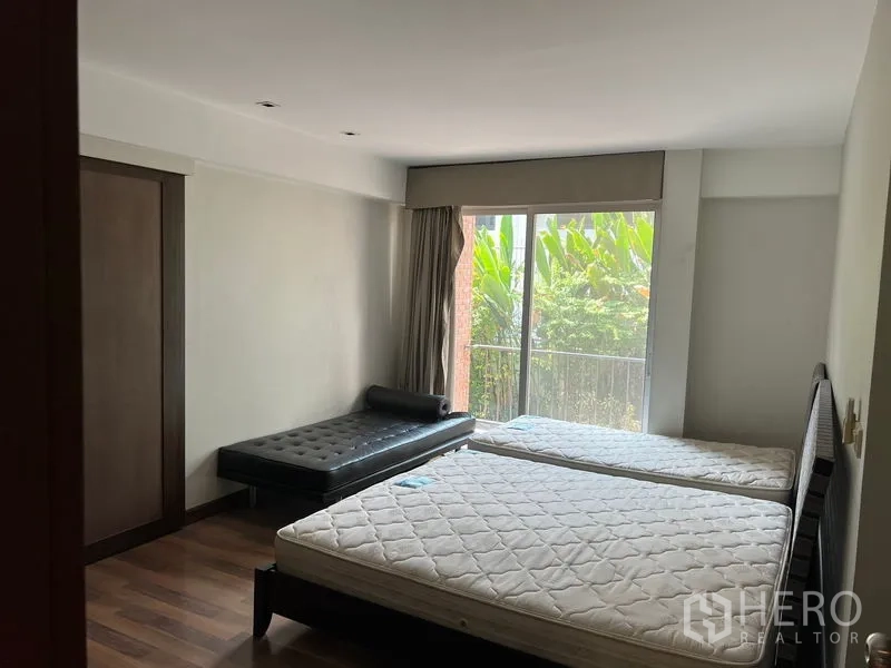 อพาร์ทเมนท์ ให้เช่าในWatthana, Bangkok - ห้องนอนที่สองเตียงคู่ พร้อมเดย์เบดและประตูกระจกออกระเบียงมองเห็นต้นไม้