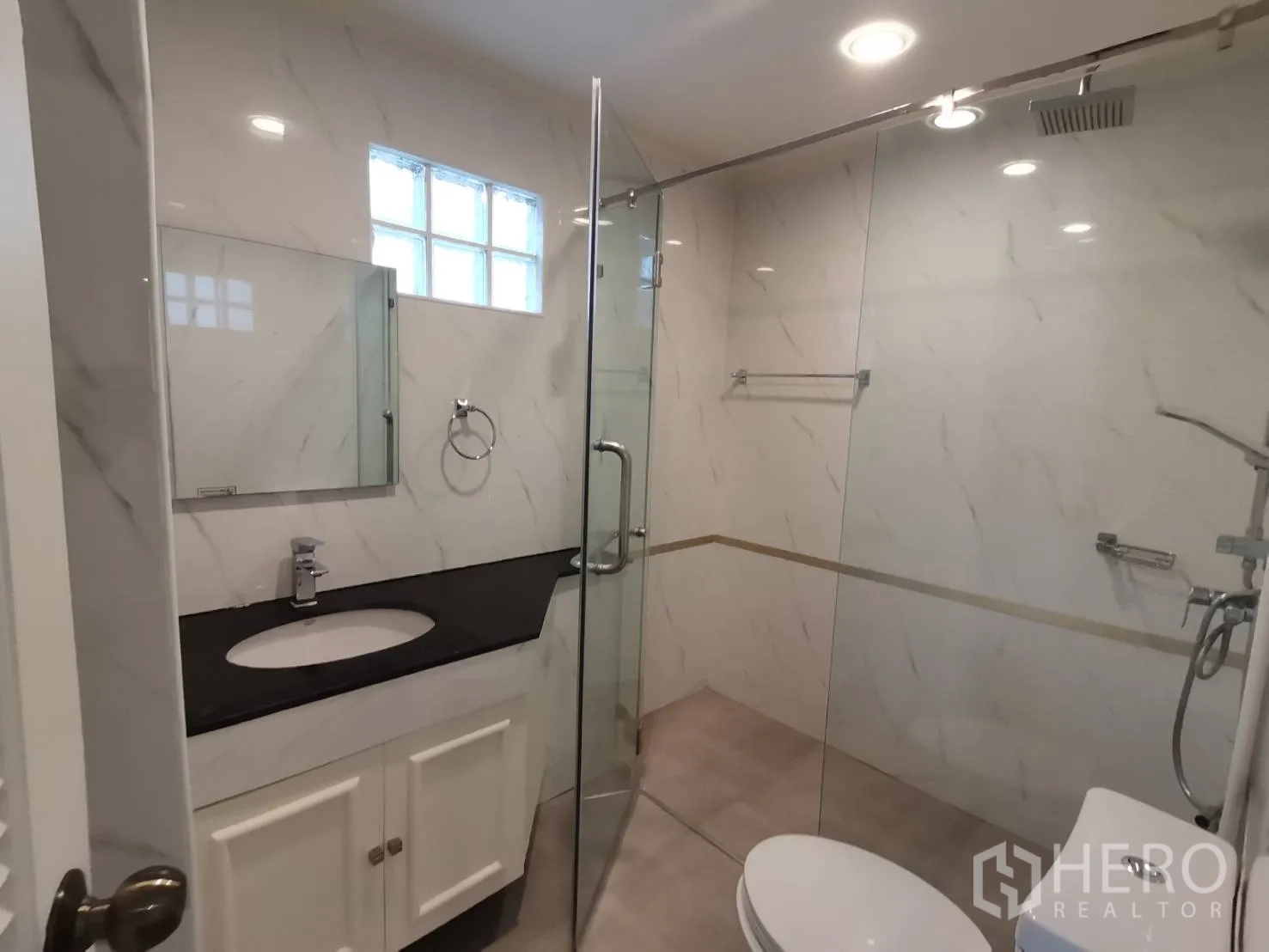 คอนโด for rent in Watthana, Bangkok - ห้องน้ำผนังลายหินอ่อน กั้นอาบน้ำกระจก และอ่างล้างหน้าพร้อมตู้
