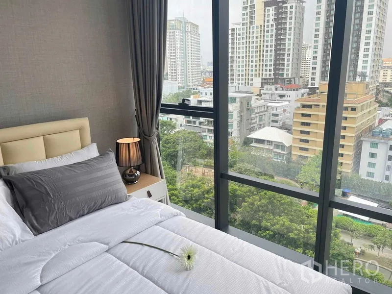 公寓 出租在Ratchathewi, Bangkok - 转角卧室，超大窗户，白色床品，城市与绿地景观。