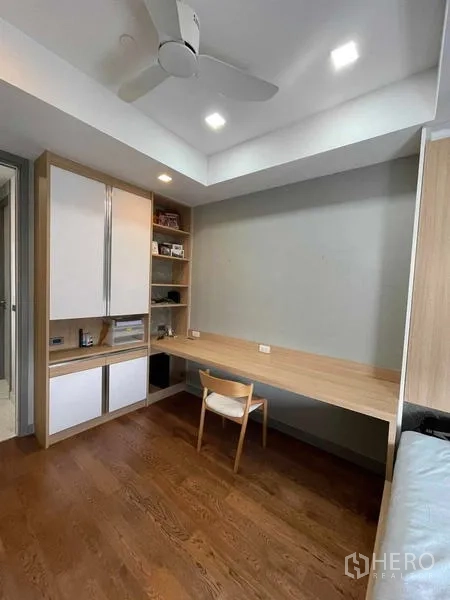 Condominium for rent or sale in Bang Rak, Bangkok - Study room with a long wooden desk, ceiling fan, and built-in cabinets and shelves.
