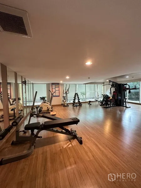 Condominium for rent in Khlong Toei, Bangkok - Condo fitness room with cardio machines, free weights and mirrored wall.