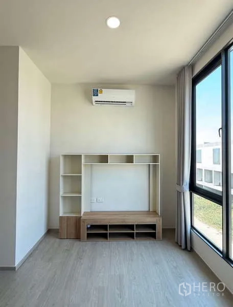 Townhouse for rent in Bang Phli, Samut Prakan - Corner room with media shelf, air conditioner and large window with curtains.
