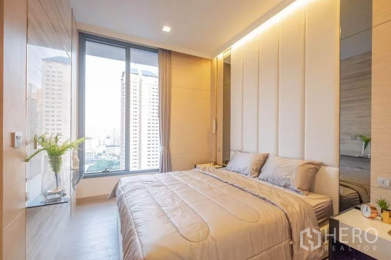 公寓 出租在Watthana, Bangkok - 舒适卧室，大窗城市景观，软包床头与内置层架。