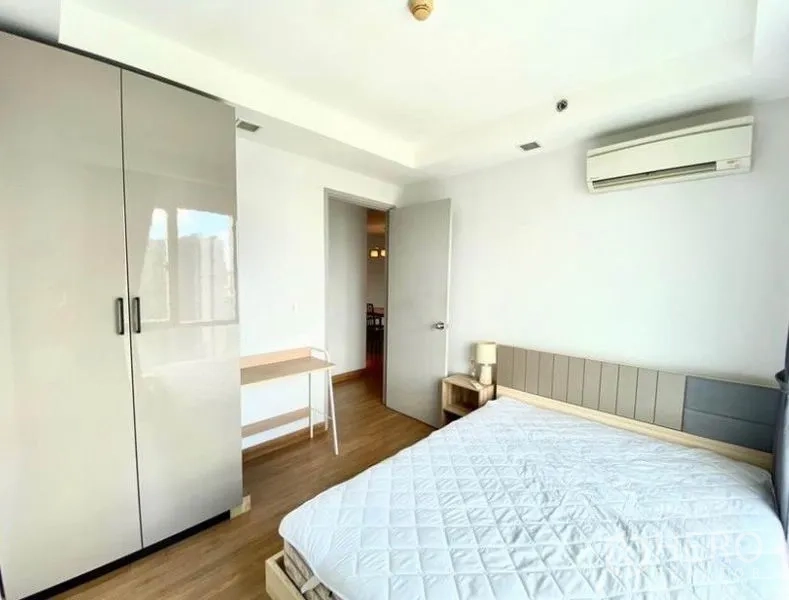 Condominium for rent in Huai Khwang, Bangkok - Second bedroom with wardrobe, desk and air conditioning.