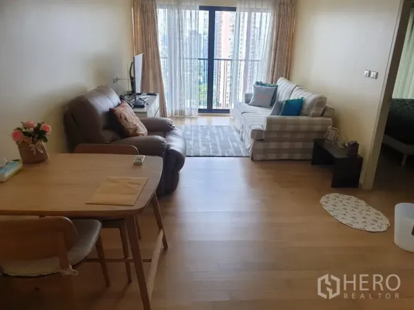 Condominium for rent or sale in Watthana, Bangkok - Bright living room with sofa, recliner, dining set and balcony city view.