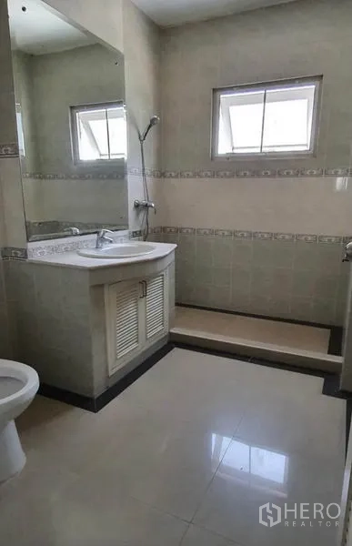 Townhouse for rent in Huai Khwang, Bangkok - Tiled bathroom with vanity, toilet and step-up shower zone with window.
