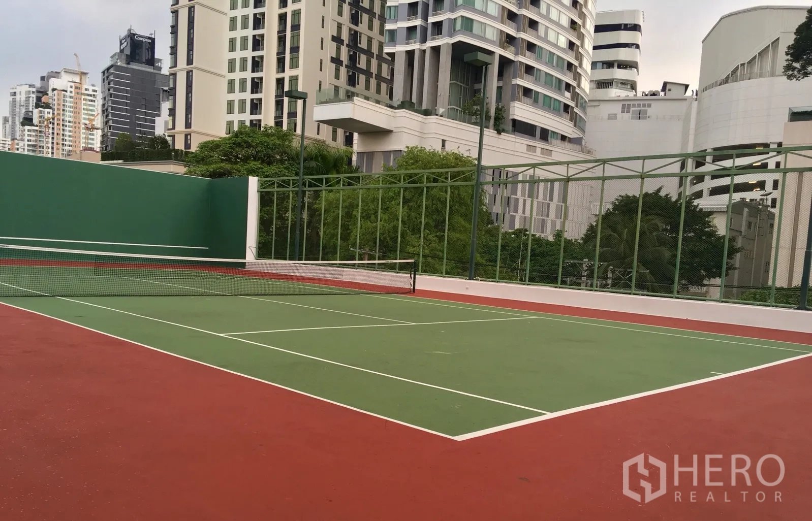 Condominium for rent or sale in Watthana, Bangkok - Full‑size tennis court within the condominium, framed by the Bangkok skyline.
