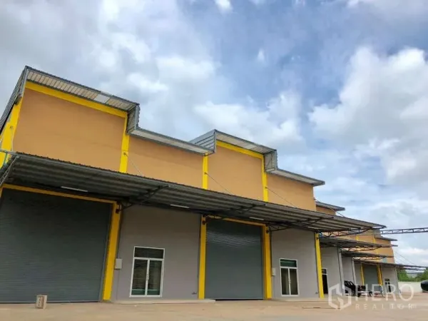 โรงงาน ให้เช่าในMueang Samut Sakhon, Samut Sakhon - อาคารโรงงานสมัยใหม่โทนเหลือง มีประตูม้วนขนาดใหญ่และหลังคาคลุมจุดขนถ่าย