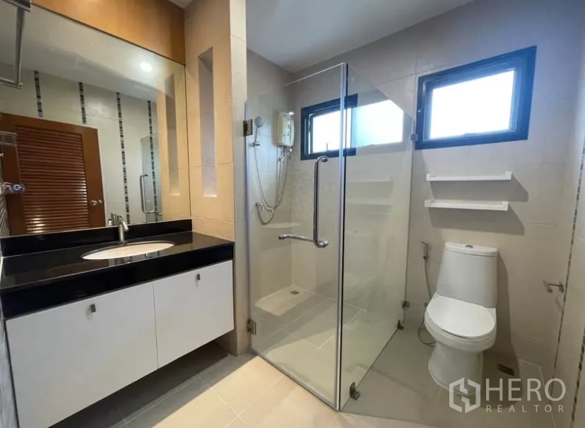 Detached House for rent in Chatuchak, Bangkok - Modern bathroom with vanity, glass shower enclosure and twin windows.