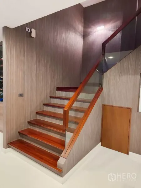 Detached House for rent or sale in Chatuchak, Bangkok - Timber staircase with glass railing and built-in storage under steps.