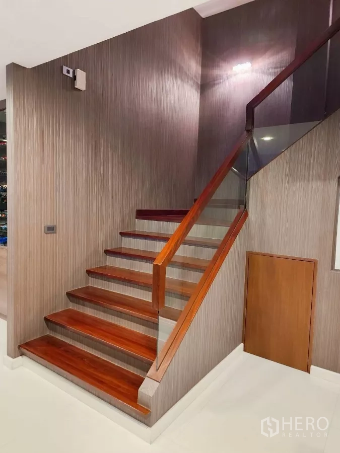 Detached House for rent or sale in Chatuchak, Bangkok - Timber staircase with glass railing and built-in storage under steps.