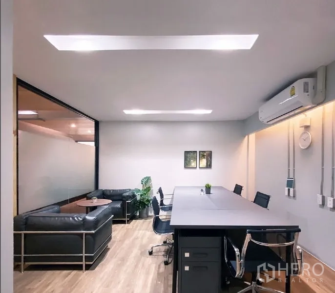 Office Space for rent in Bang Rak, Bangkok - Team workspace featuring a long table, leather sofa lounge, wall art, and ceiling lights.