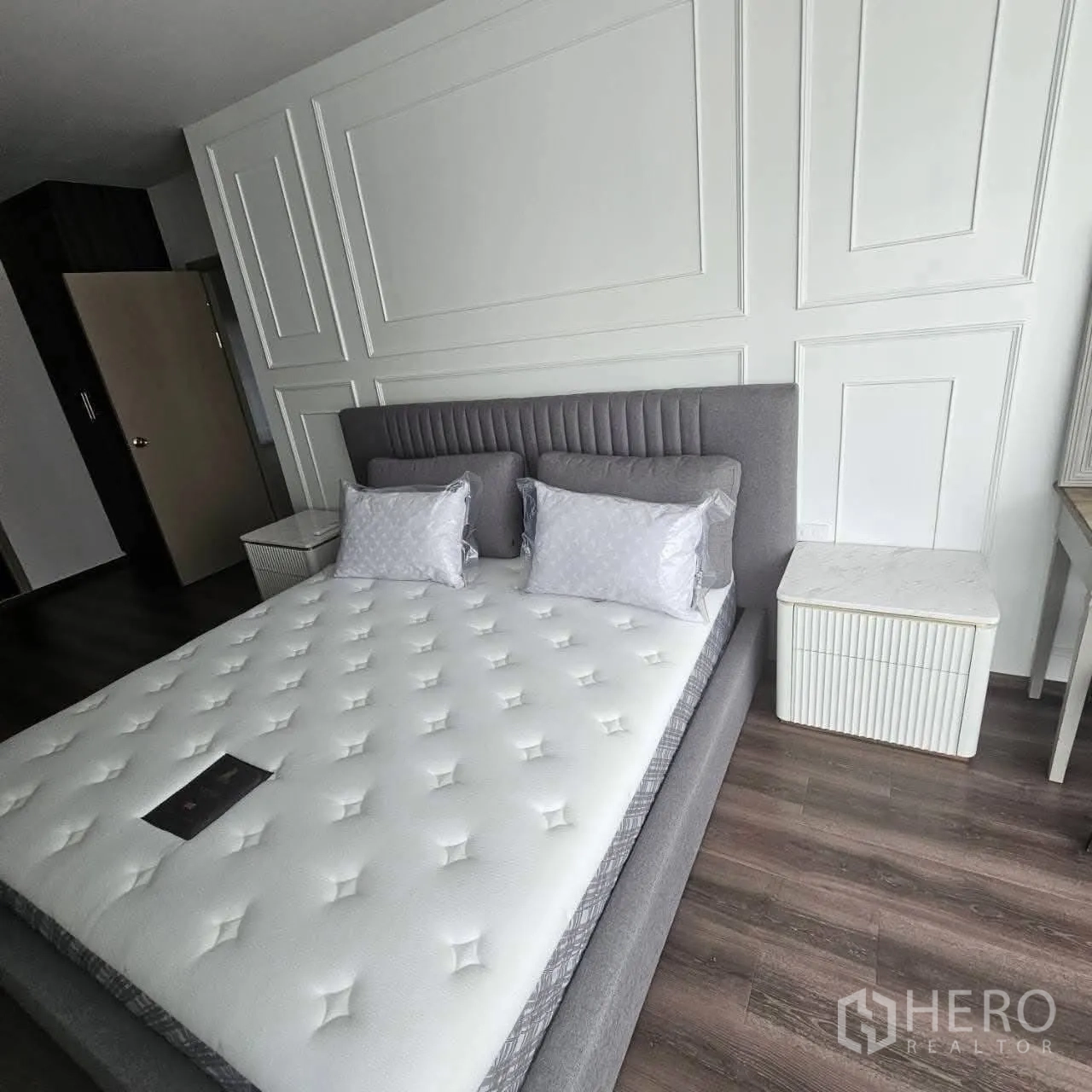 คอนโด for rent in Huai Khwang, Bangkok - มุมห้องนอนแสดงเตียงบุผ้า ผนังตกแต่ง และตู้ข้างเตียง