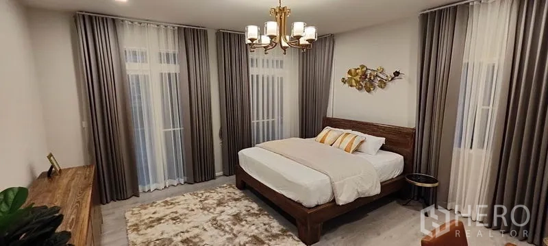 Detached House for rent in Prawet, Bangkok - Master bedroom with king bed, chandelier, sheer curtains, and accent wall art.