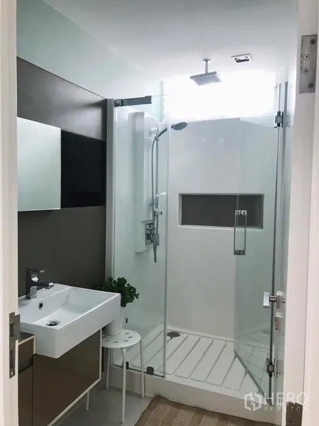 Condominium for rent in Bang Rak, Bangkok - Second bathroom with glass shower, rain shower head and compact vanity.
