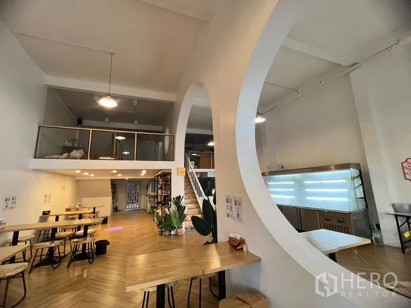 Shophouse for rent in Phra Khanong, Bangkok - Spacious shophouse hall with large circular arch, mezzanine, staircase and display chiller.