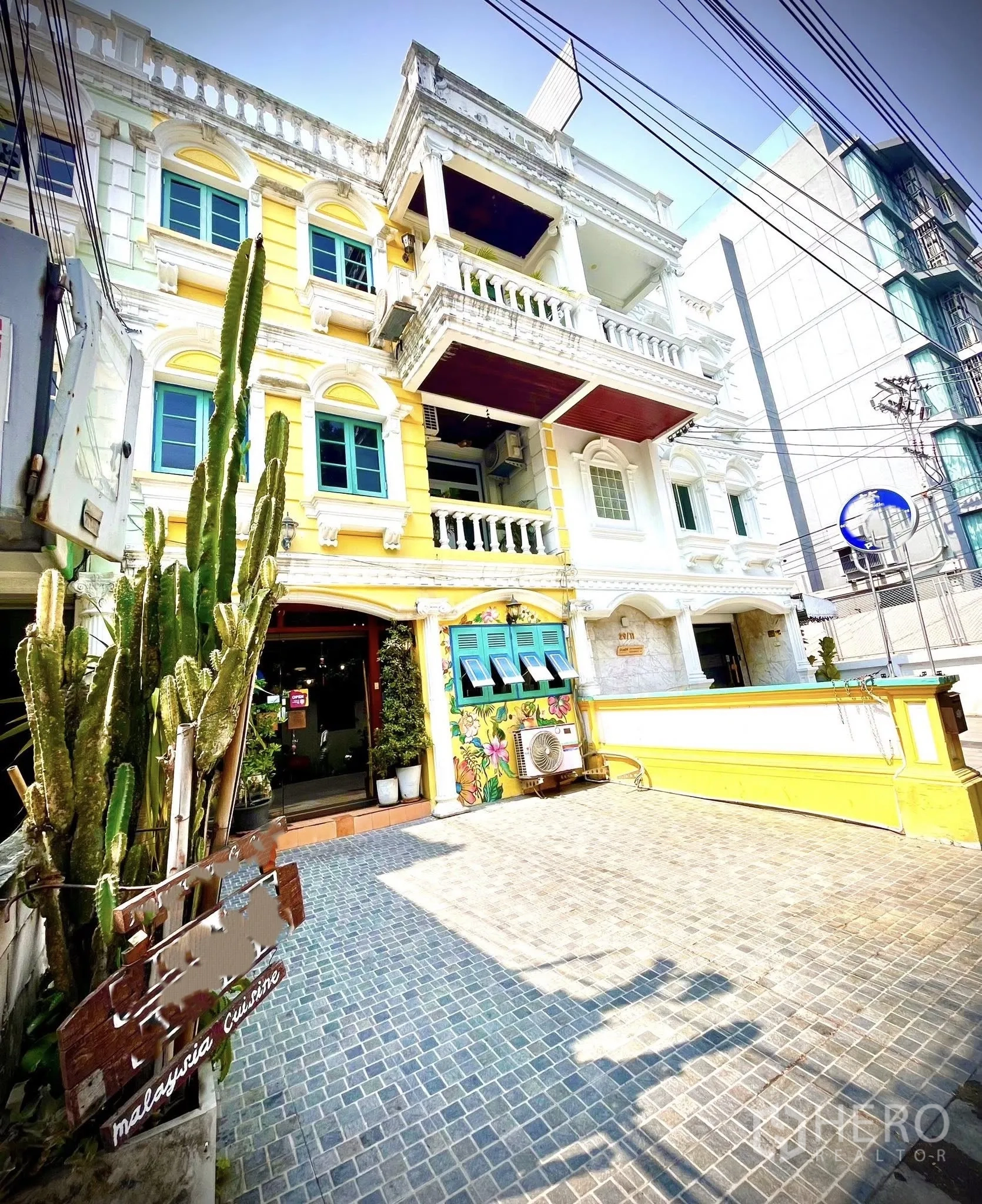 Retail Space for rent in Watthana, Bangkok - Colorful shophouse exterior with yellow facade, balconies, blue window frames, and a paved forecourt.