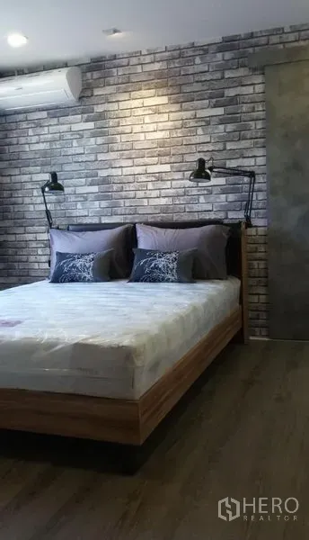 公寓 出租或出售在Watthana, Bangkok - 卧室配砖纹特色墙、木床、床头壁灯与空调。