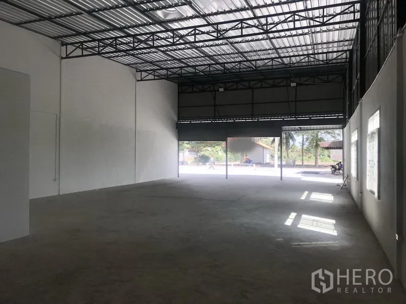 货栈 出租在Lam Luk Ka, Pathum Thani - 从内部望向入口，两扇大型卷帘门与充足自然光。