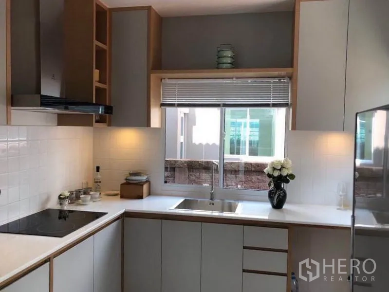 Detached House for rent in Suan Luang, Bangkok - Modern L-shaped kitchen with white countertops, hob, hood and window over the sink.