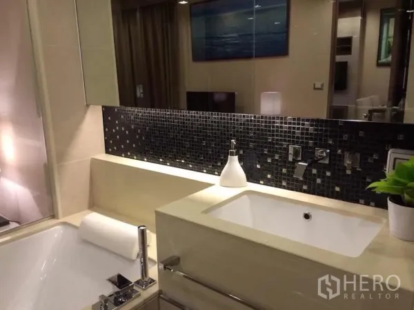 Condominium for rent or sale in Bang Rak, Bangkok - Modern bathroom with built-in bathtub, rectangular sink and mosaic tile backsplash