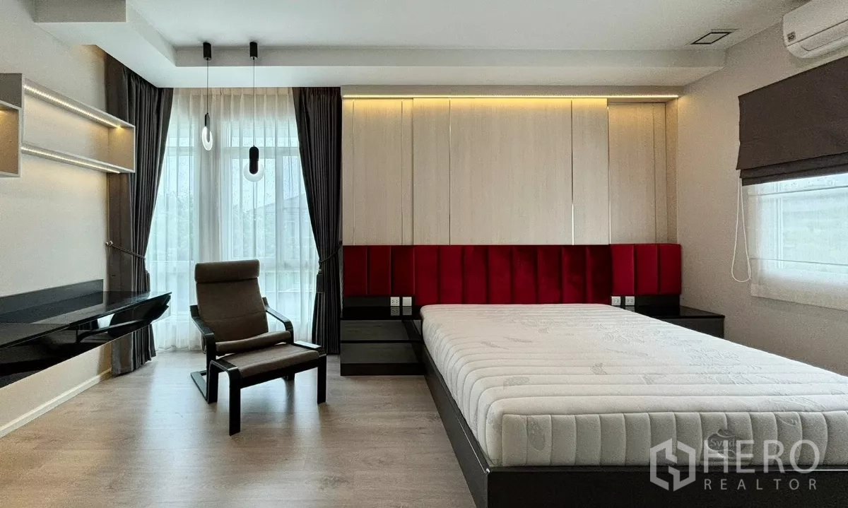 Detached House for rent or sale in Prawet, Bangkok - Second bedroom with red upholstered headboard, built-in wardrobes and work desk by the window.