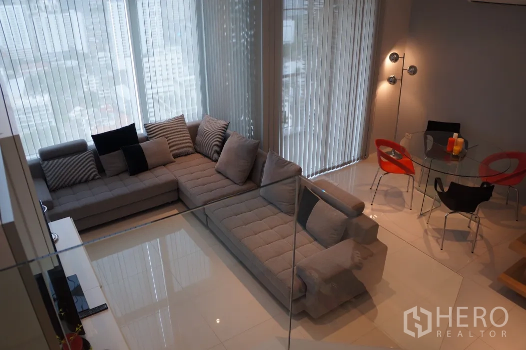 Condominium for rent in Ratchathewi, Bangkok - Bright living and dining area with L-shaped sofa, floor-to-ceiling windows and city views.