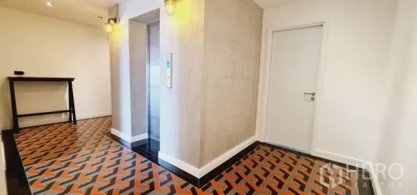 Condominium for rent in Watthana, Bangkok - Lift lobby with geometric patterned tiles, wall sconces and concrete-finish walls.