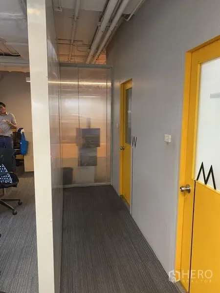Office Space for rent in Khlong Toei, Bangkok - Hallway with yellow doors and glass partitions leading to a modern workspace.