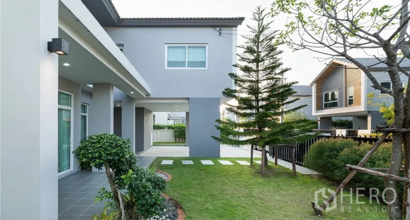 บ้าน ขายในLam Luk Ka, Pathum Thani - สวนหลังบ้านสนามหญ้า ต้นสน ทางเดินแผ่นทาง และระเบียงหลังคา