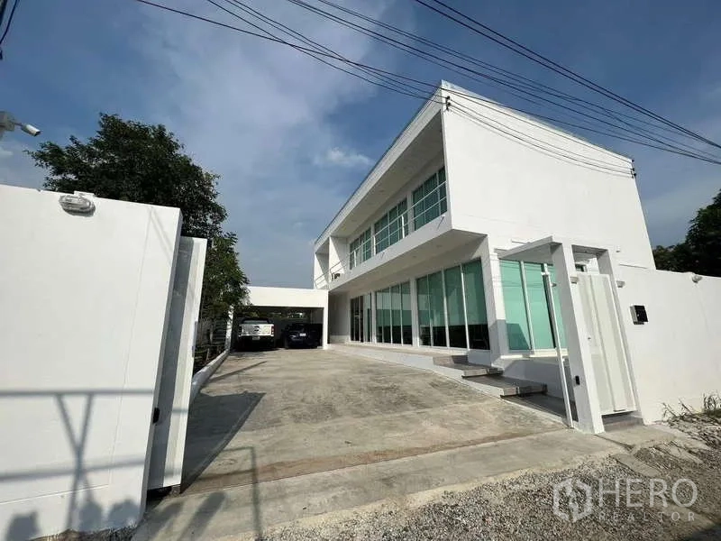 Detached House for rent in Lat Krabang, Bangkok - Front exterior of a modern white detached house with wide driveway and large windows.