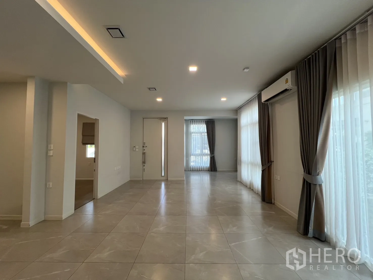 独立式住宅 出租在Prawet, Bangkok - 客厅朝入户门与整面高窗视角。