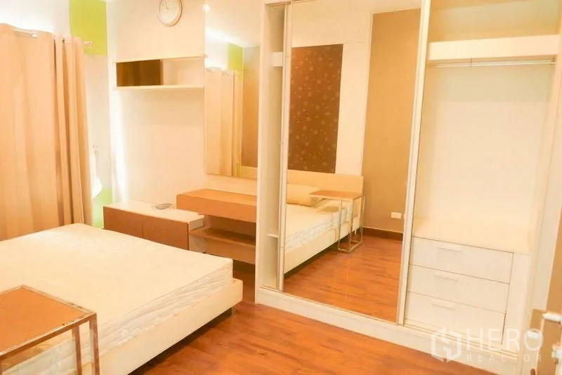 Condominium for rent or sale in Khlong San, Bangkok - Master bedroom with mirrored wardrobe, dressing table and warm wood floors.