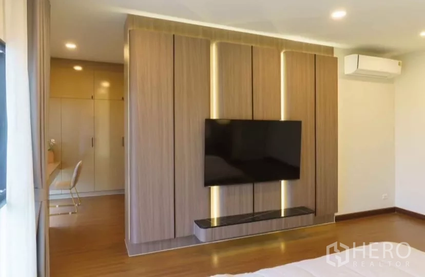 独立式住宅 出租或出售在Bang Phli, Samut Prakan - 卧室带木质电视墙、嵌入式衣柜与书桌。
