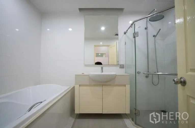 Condominium for rent or sale in Khlong Toei, Bangkok - Modern bathroom with bathtub, glass shower, vanity and large mirror.
