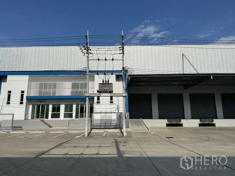 Factory for rent in Bang Sao Thong, Samut Prakan - Front elevation showing office block, transformer, and multiple dock-high roller shutters.