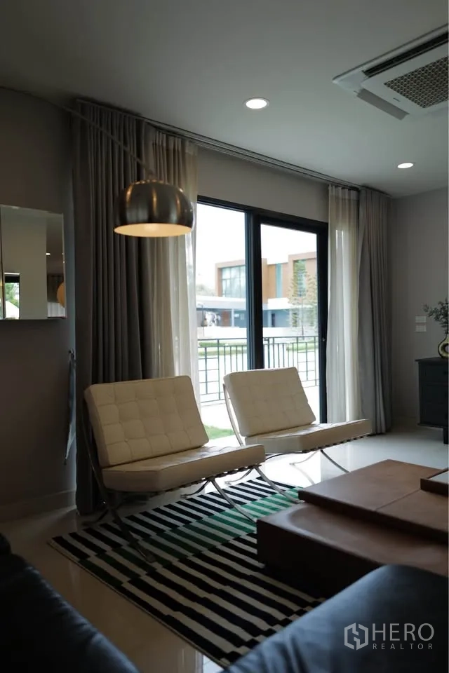 Detached House for rent or sale in Bang Phli, Samut Prakan - Living area with two lounge chairs by full-height windows and a floor lamp.