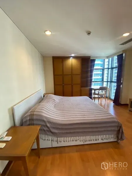 公寓 出租在Pathum Wan, Bangkok - 主卧配大床与木质衣柜，转角窗旁设书桌。