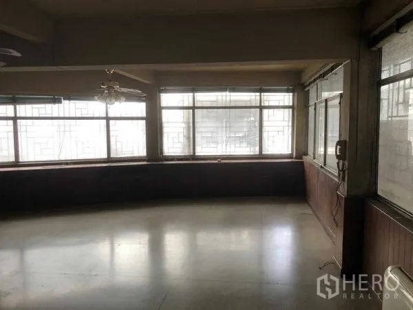 Shophouse for rent in Khlong Toei, Bangkok - Bright corner room with large grid-pattern windows and wood wainscoting.