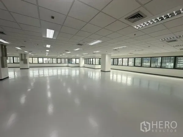 Office Space for rent in Bang Rak, Bangkok - Large vacant office interior with multiple panoramic windows, central air vents, and smooth grey floors.
