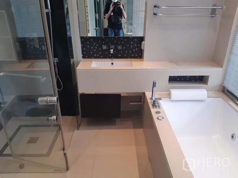 Condominium for rent in Khlong Toei, Bangkok - Modern bathroom with wide vanity, soaking bathtub and window.