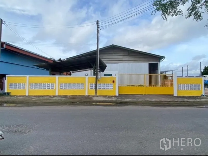 货栈 出租在Mueang Rayong, Rayong - 面向街道的仓库外观，黄色围墙与大门。