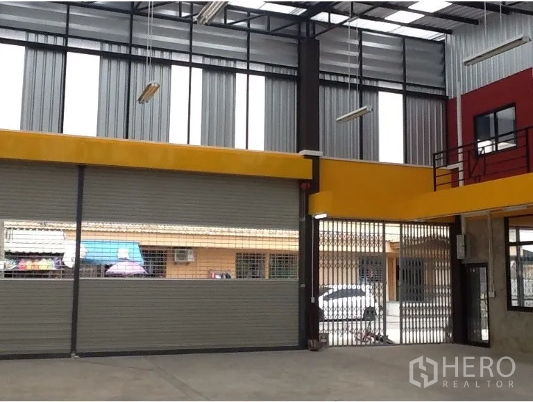 Warehouse for rent in Bang Kapi, Bangkok - Wide roller shutters and gated entry providing truck access to the warehouse floor.